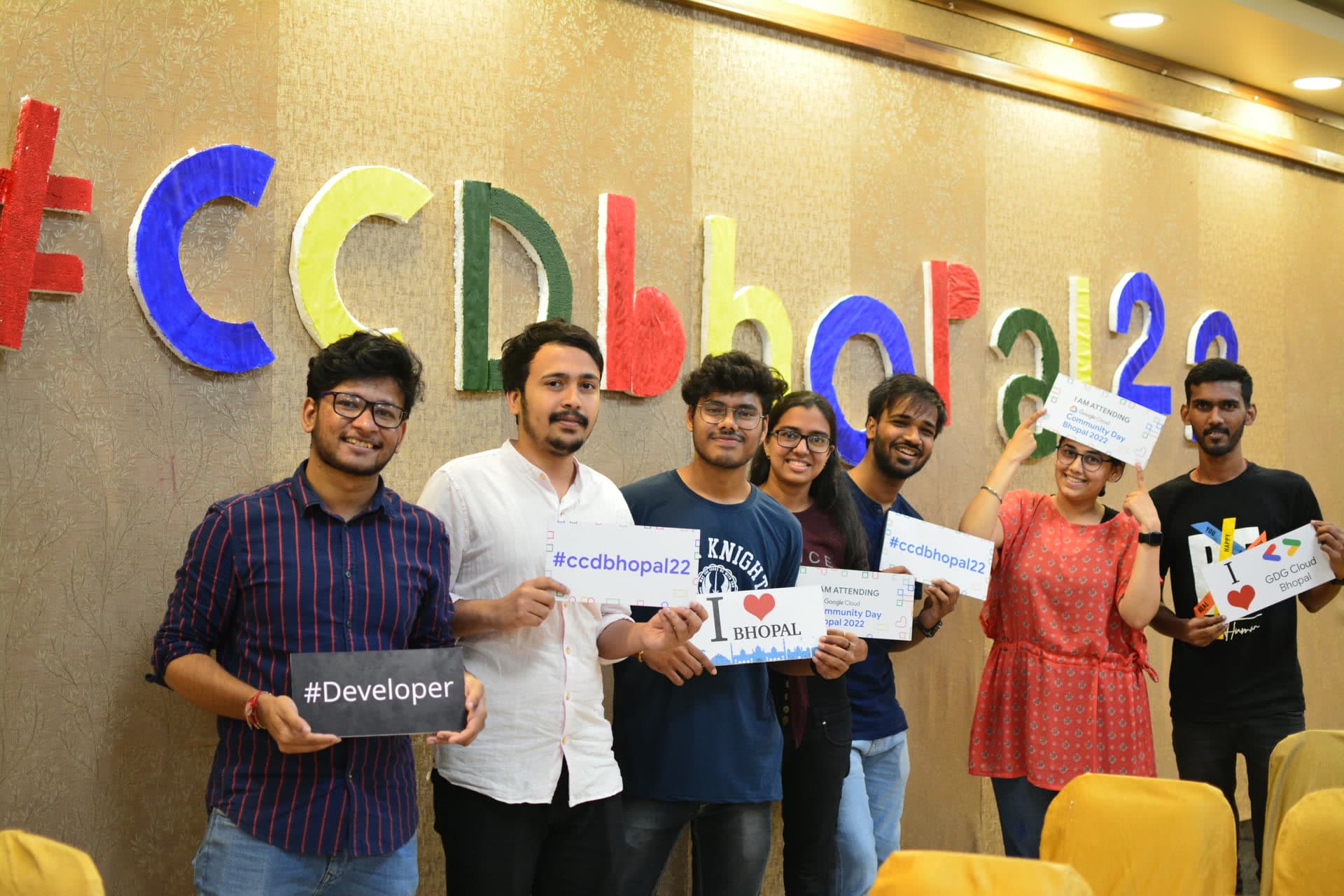 Organizers and student volunteers smiling and holding #Developer and I Love GDG Cloud Bhopal placards at Google Cloud Community Day 2022